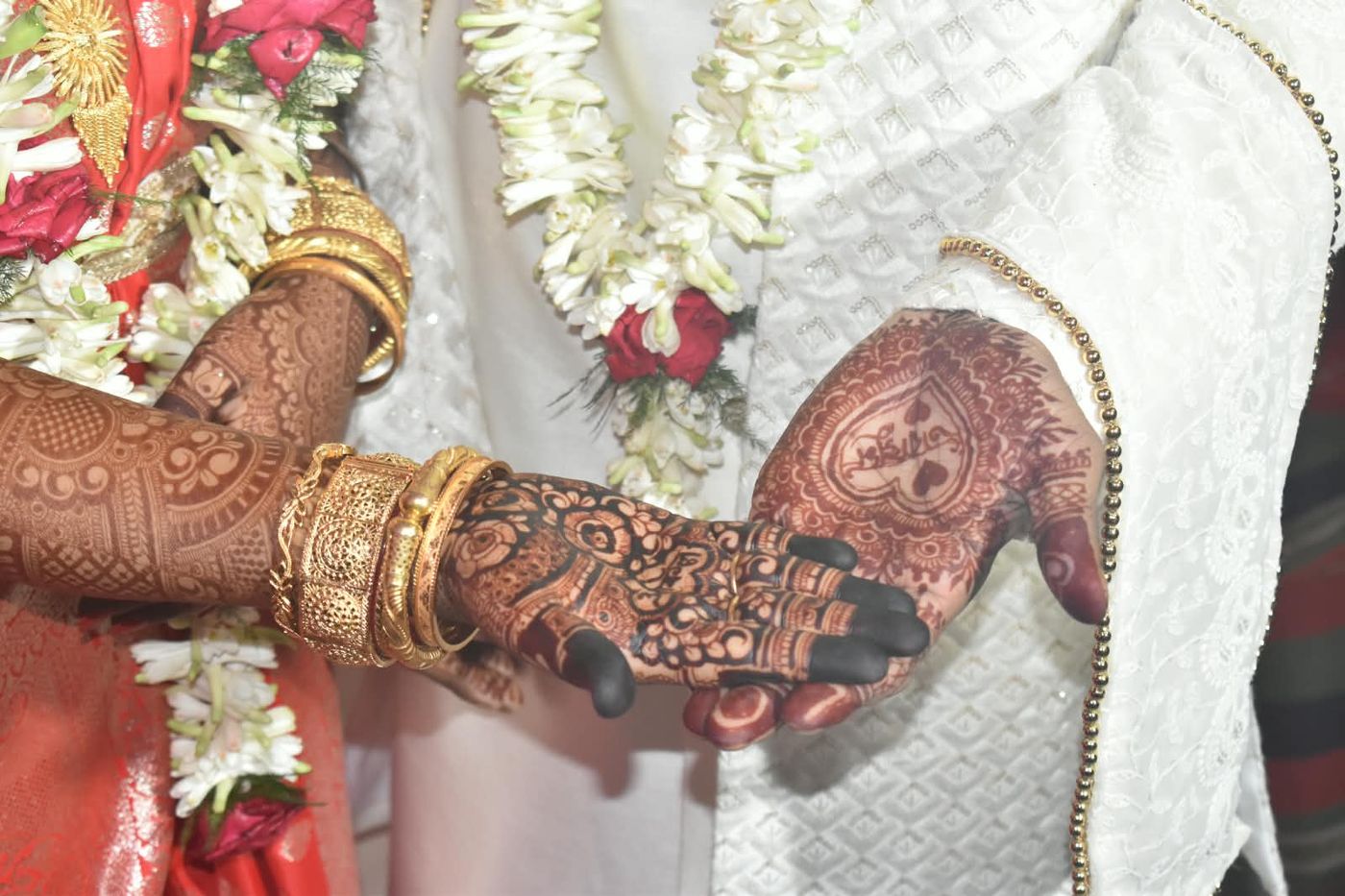 Mehndi-decorated hand resting on Sakil's wedding sherwani